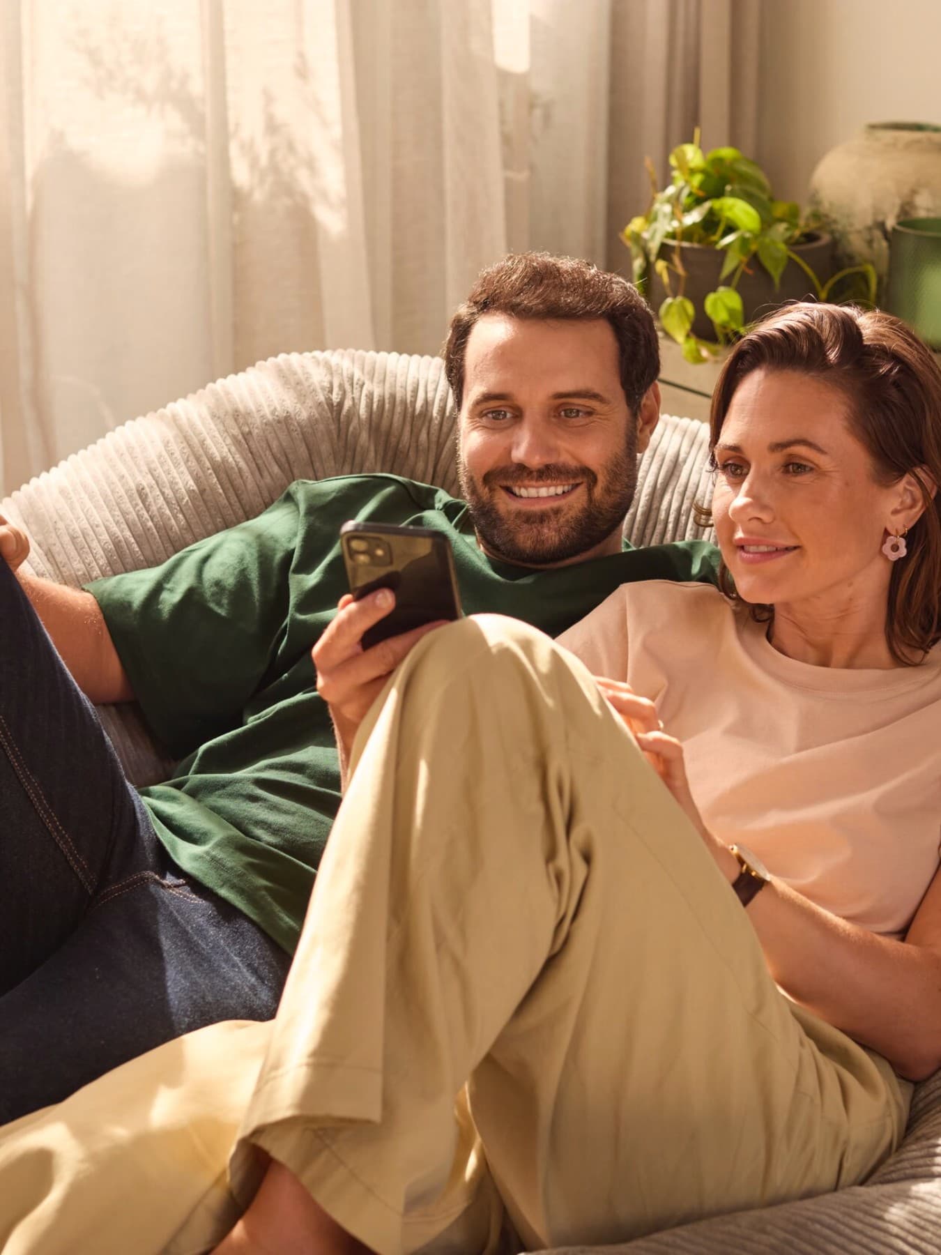 Casal sentado num sofá a olhar para um smartphone