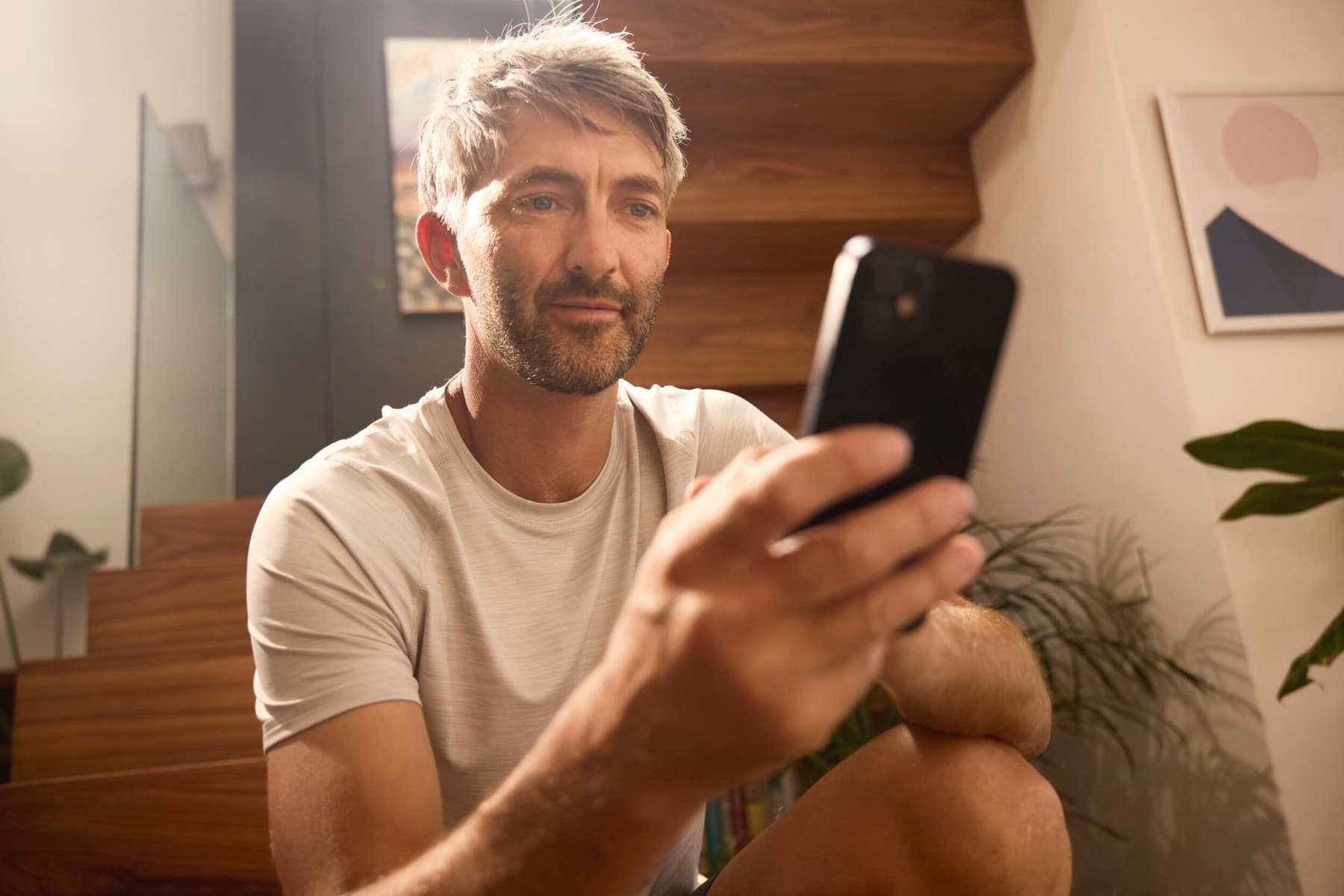 Homem sentado, descontraído, a olhar para o seu smartphone