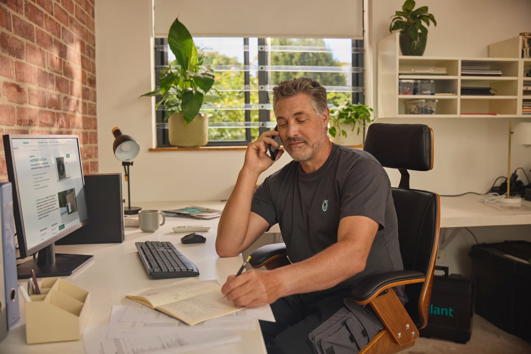 Instalador sentado no escritório a falar ao telemóvel