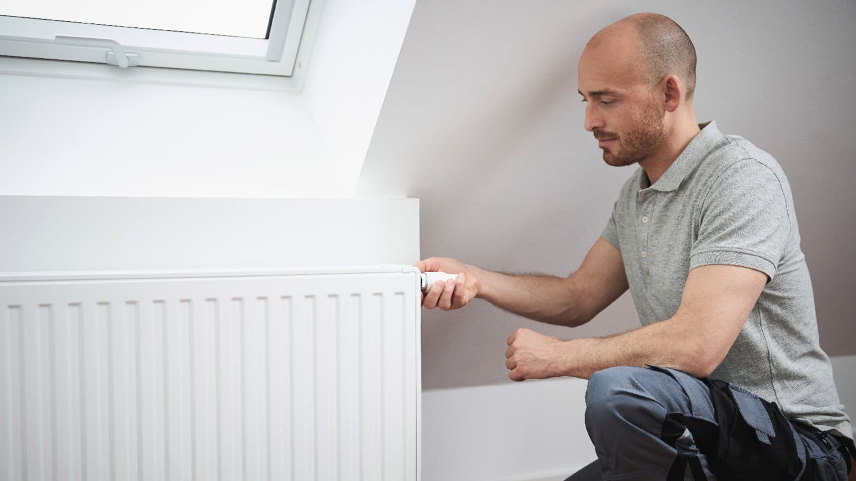 Homem a ligar o termóstato de um radiador