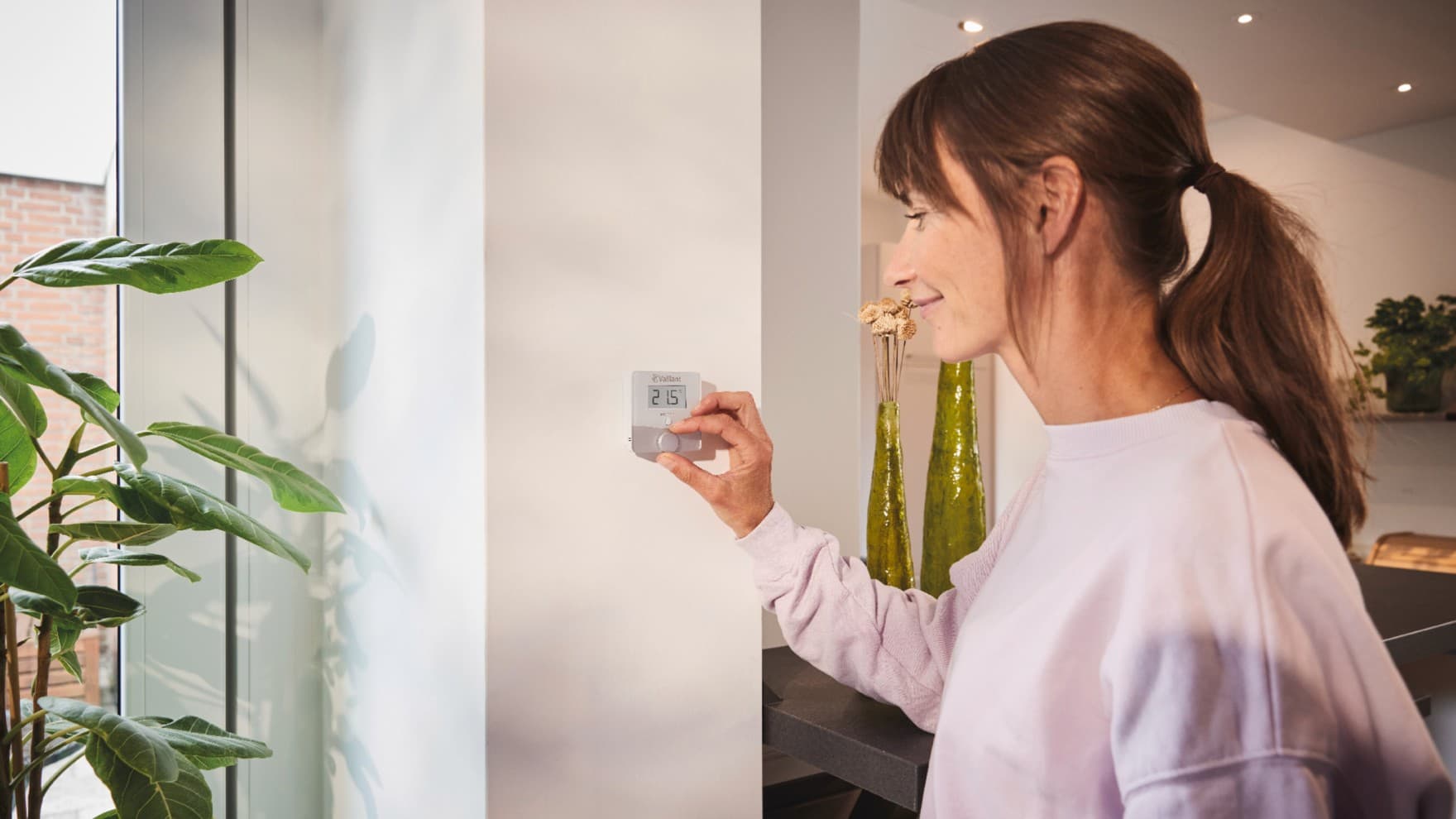 Mulher a utilizar o termóstato sensoROOM da Vaillant