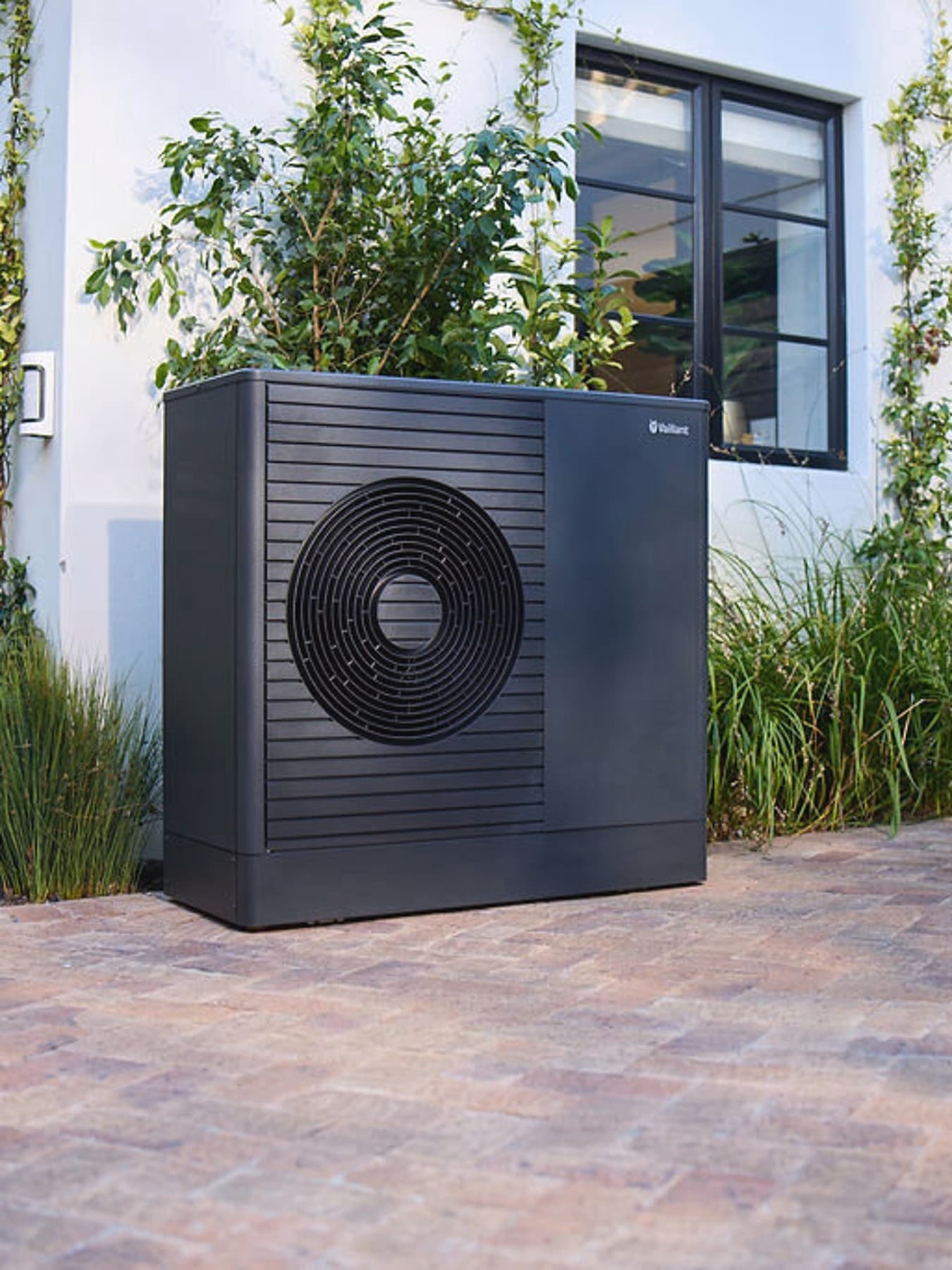 Bomba de calor antracite Vaillant aroTHERM plus no jardim da frente de uma casa