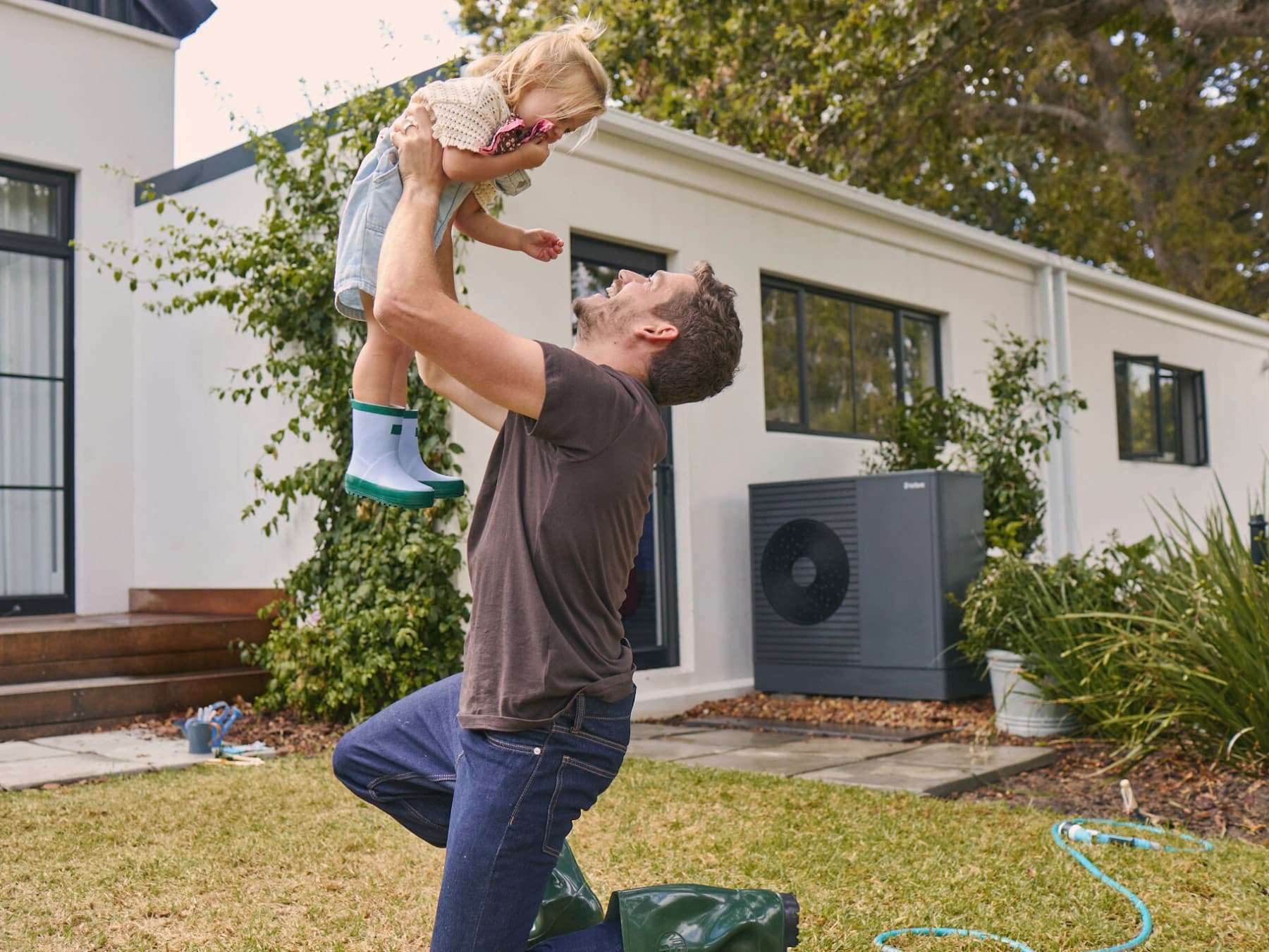 Um homem e a sua filha a brincar em frente a uma unidade exterior aroTHERM plus