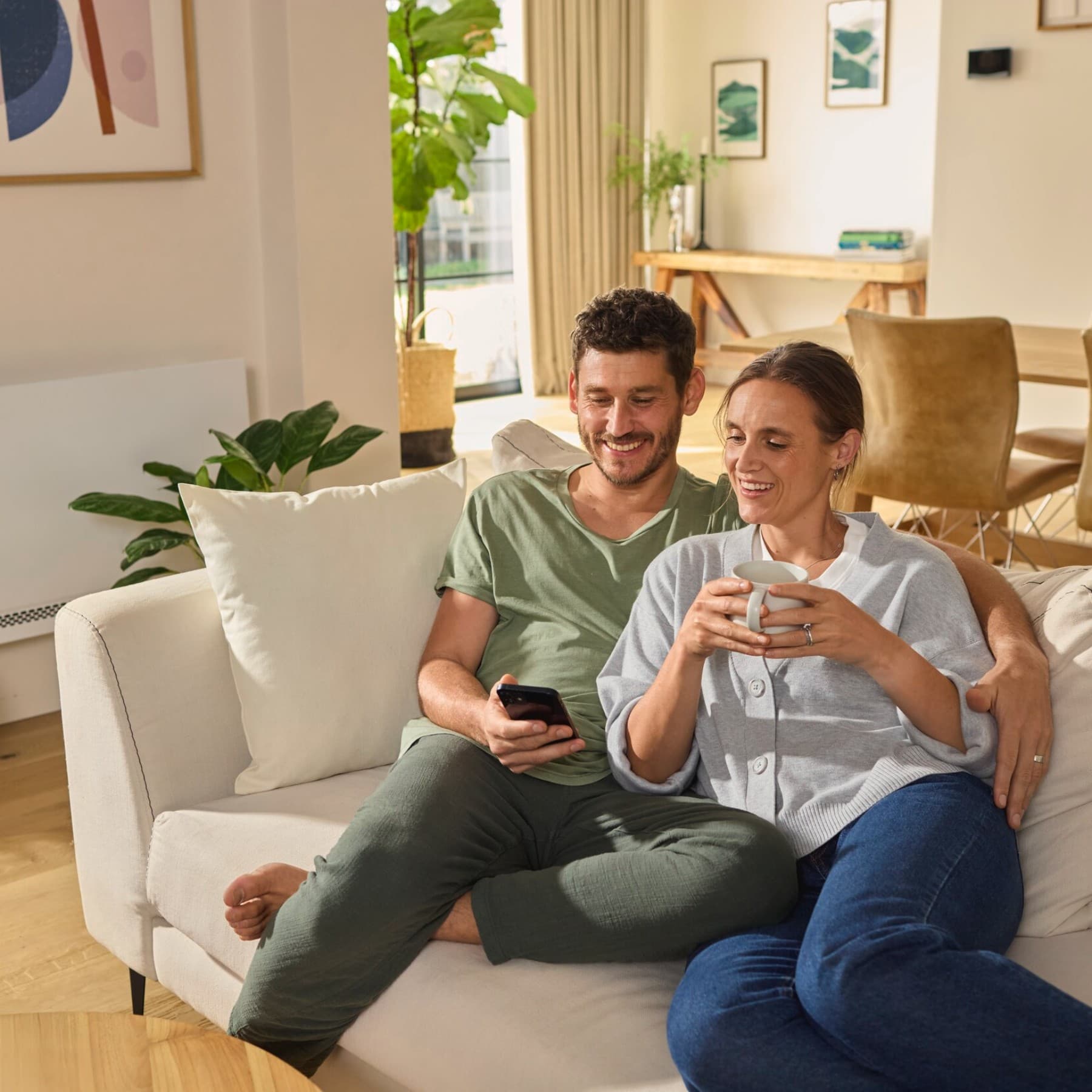 Casal sentado no sofá a olhar para um smartphone