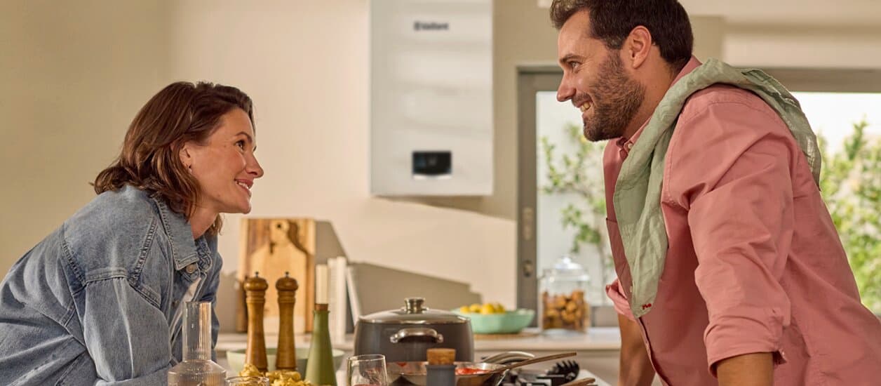 Um casal em pé na cozinha, a olhar um para o outro