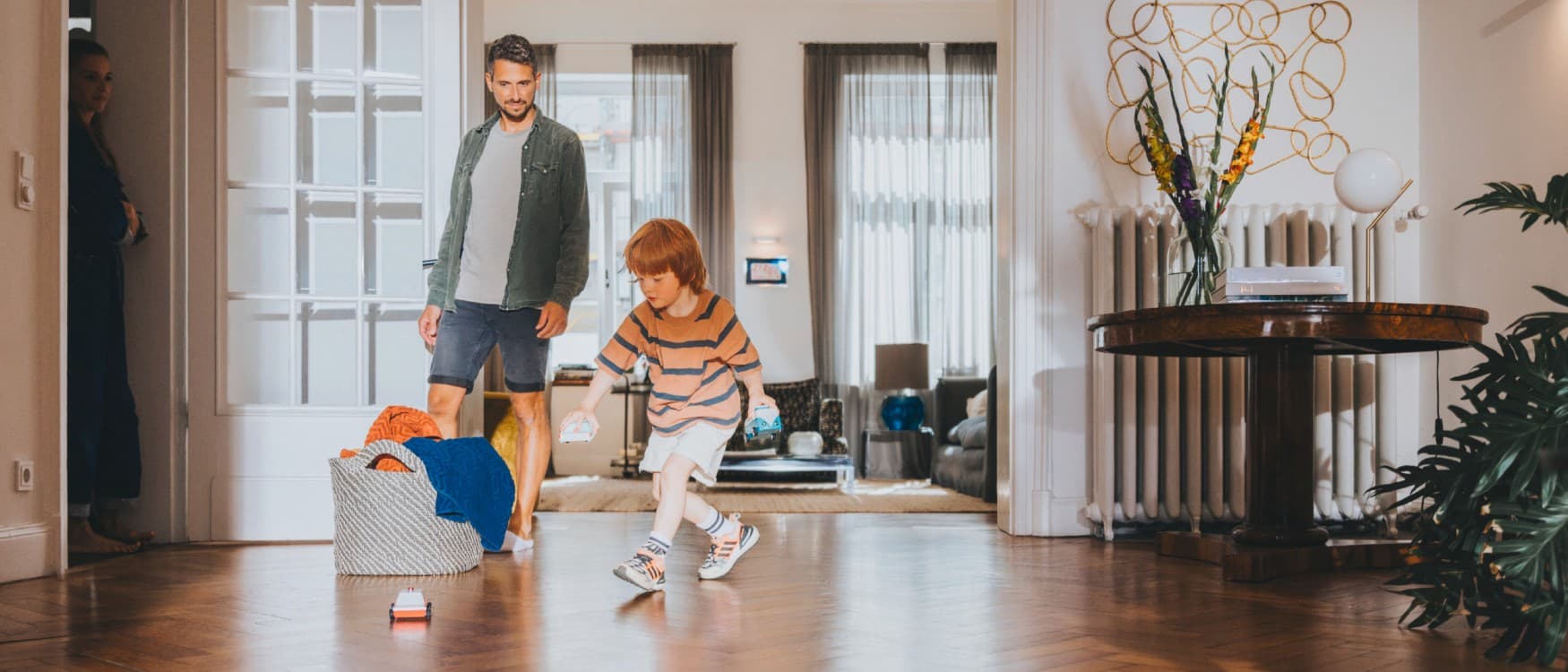O pai observa o filho a brincar na sala de estar.