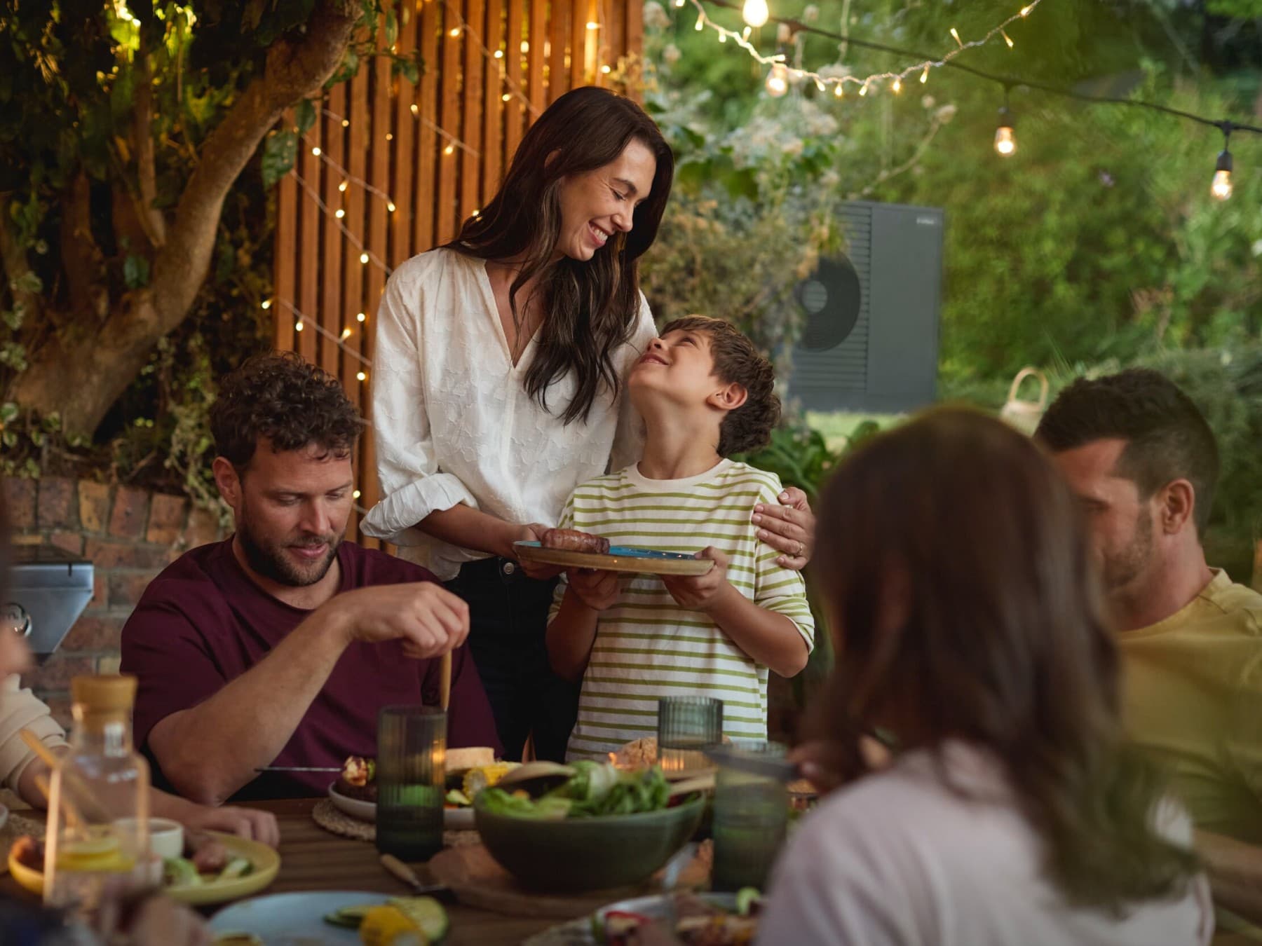 Família a desfrutar de um churrasco no jardim com amigos