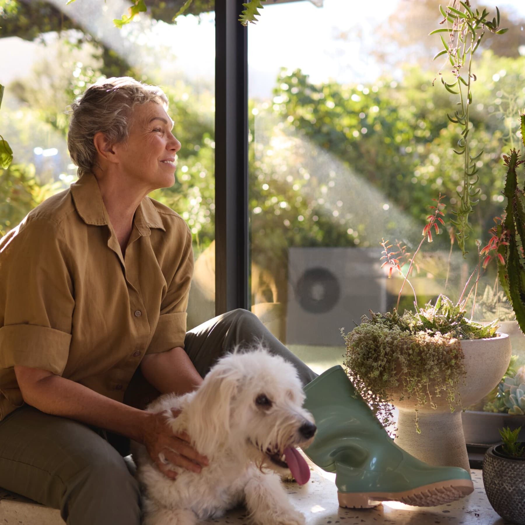 Uma senhora e o seu cão, deitados confortavelmente na sala de estar, a olhar para o jardim
