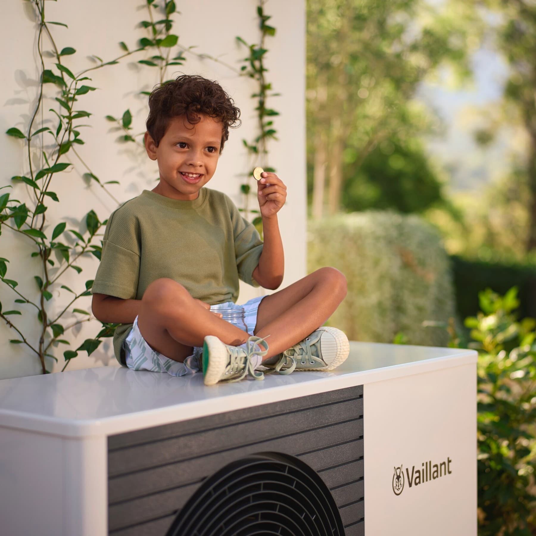Um menino segurando uma moeda numa bomba de calor
