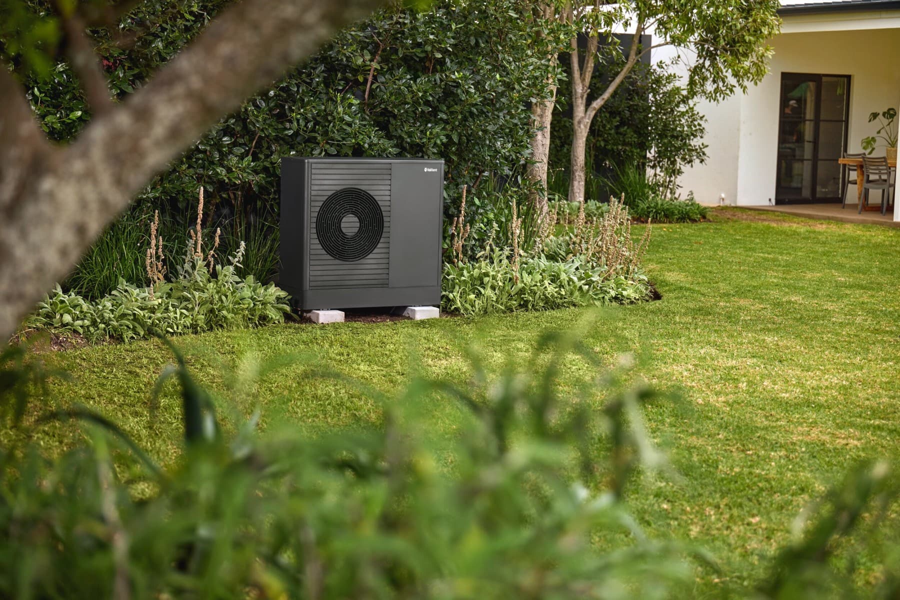 Bomba de calor Vaillant no jardim em frente a uma casa.