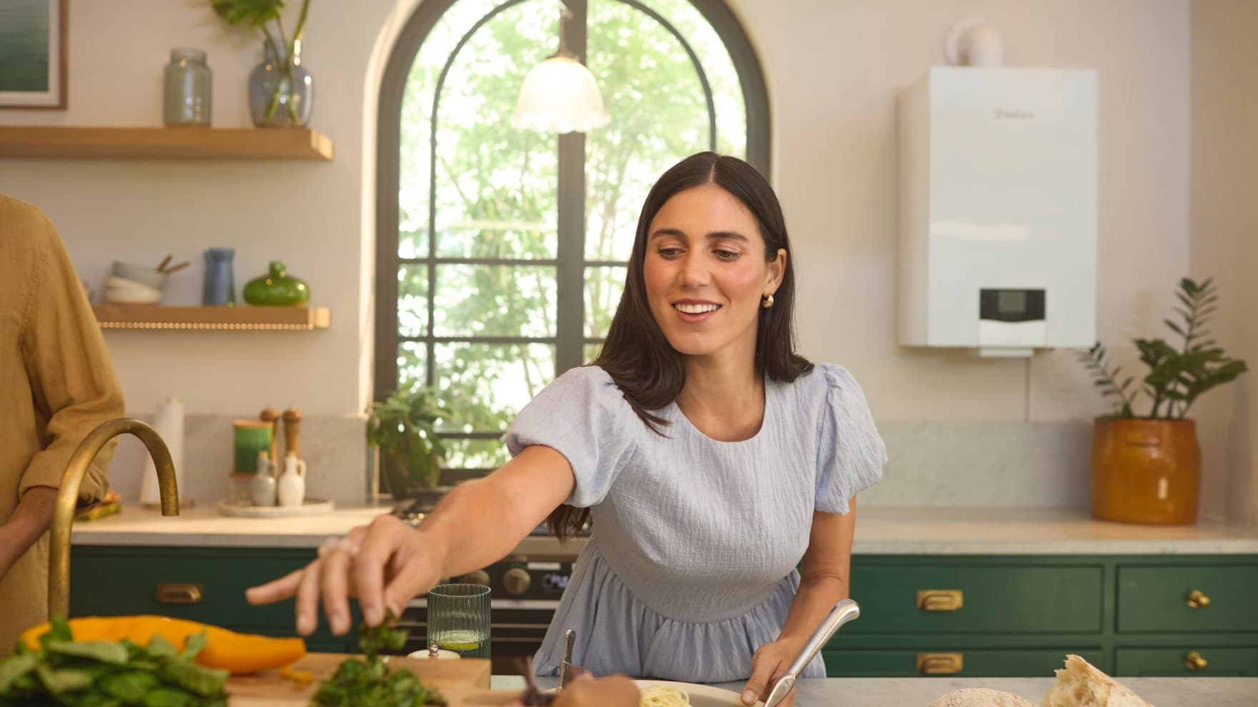 Mulher numa cozinha em frente a uma caldeira