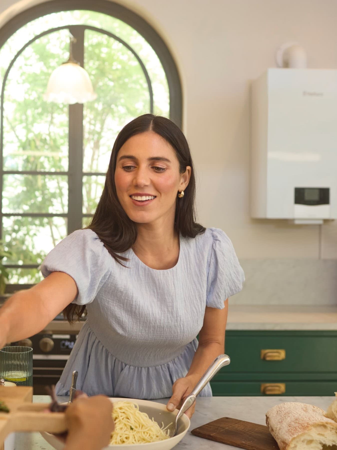 Mulher numa cozinha em frente a uma caldeira