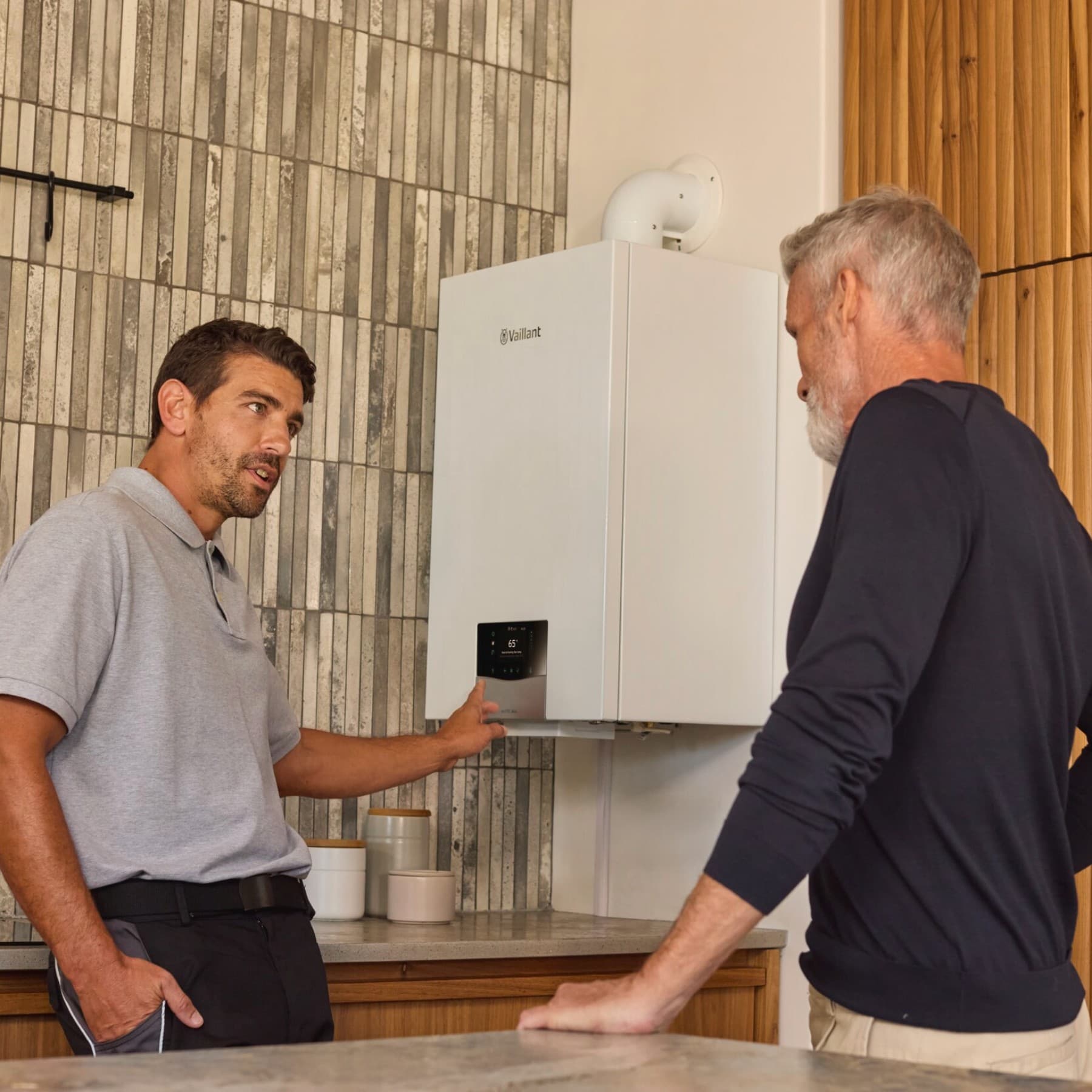 Um instalador aponta para a caldeira enquanto explica a um cliente